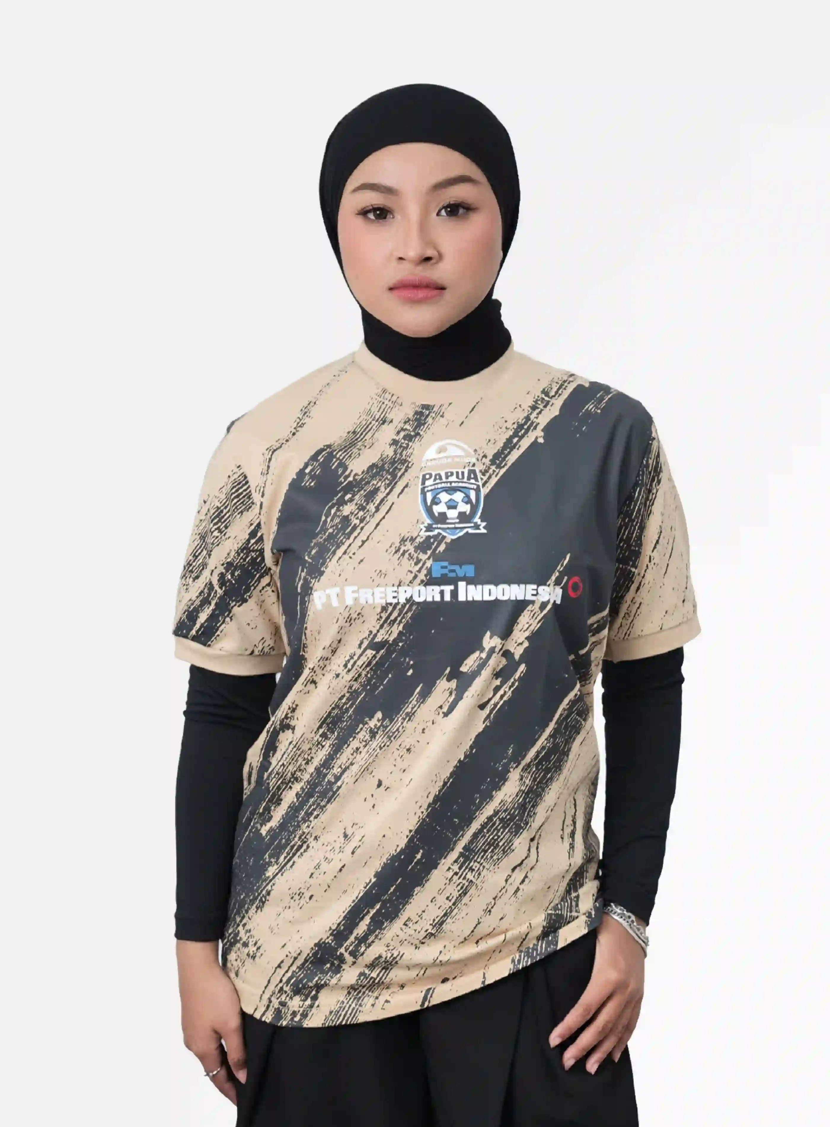 Kaos jersey motif abstrak dengan logo Garuda Muda Papua Football Academy dan PT Freeport Indonesia